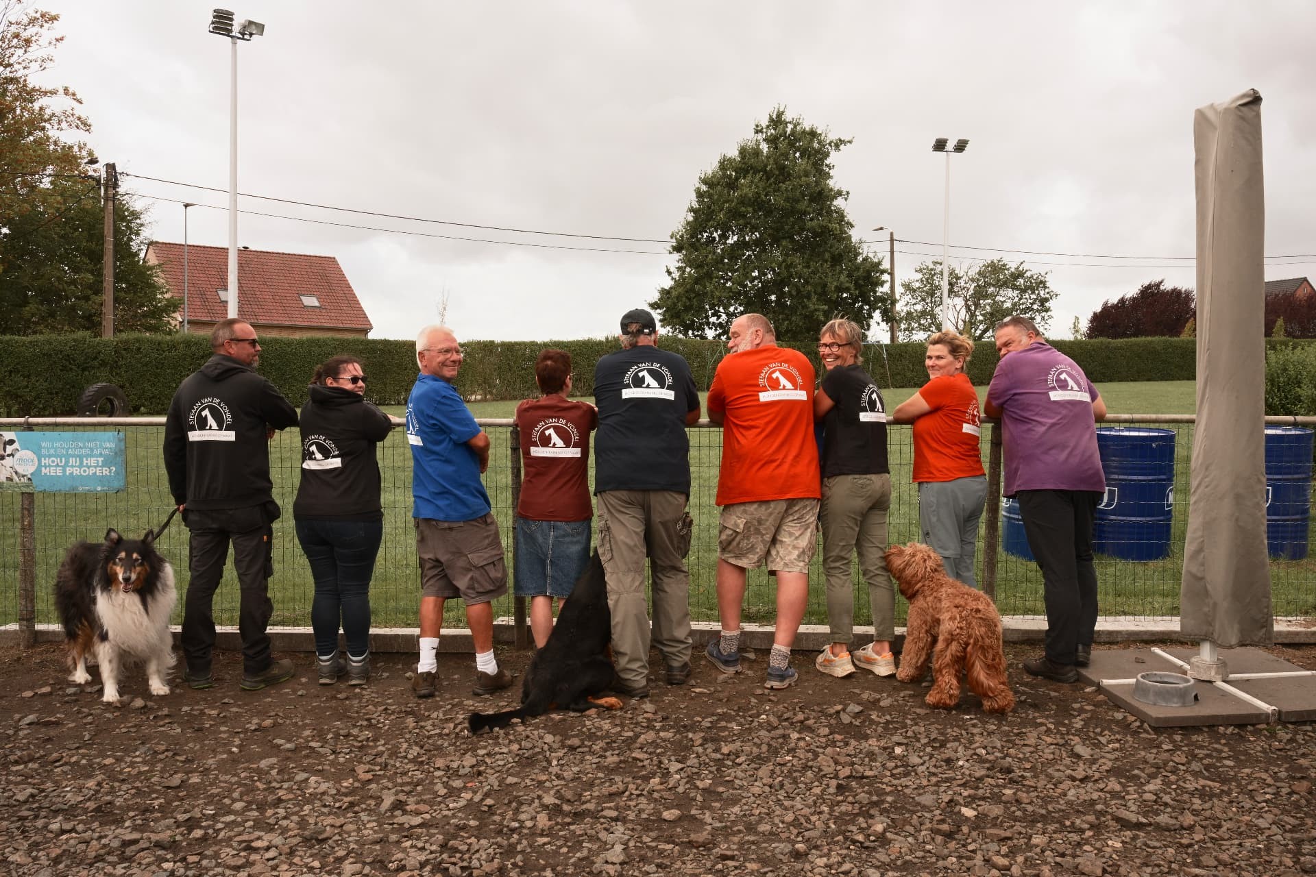 Cursisten met hun honden in de clubkleding van de hondenschool