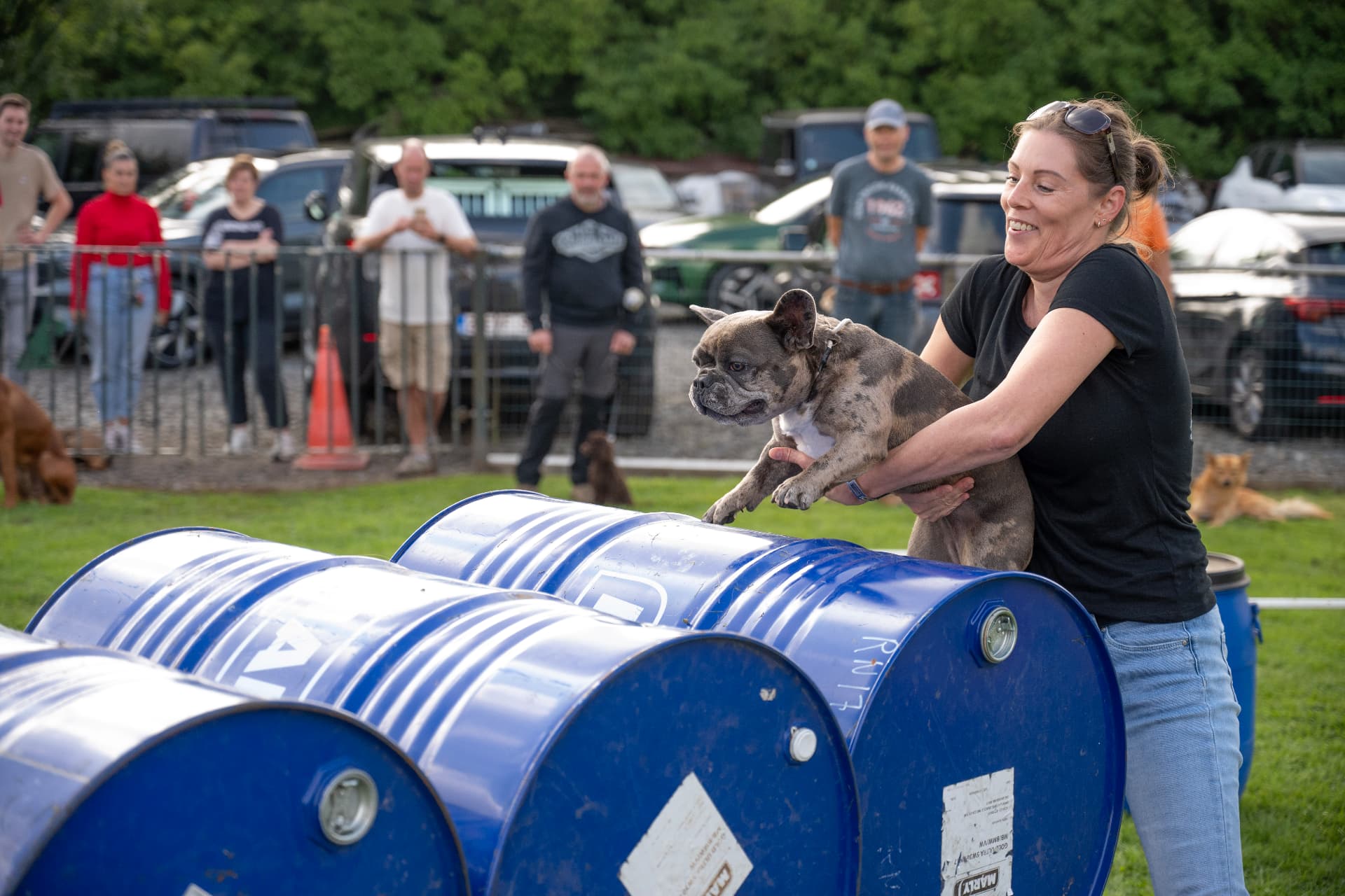 Baasje helpt een Franse bulldog over de tonnen