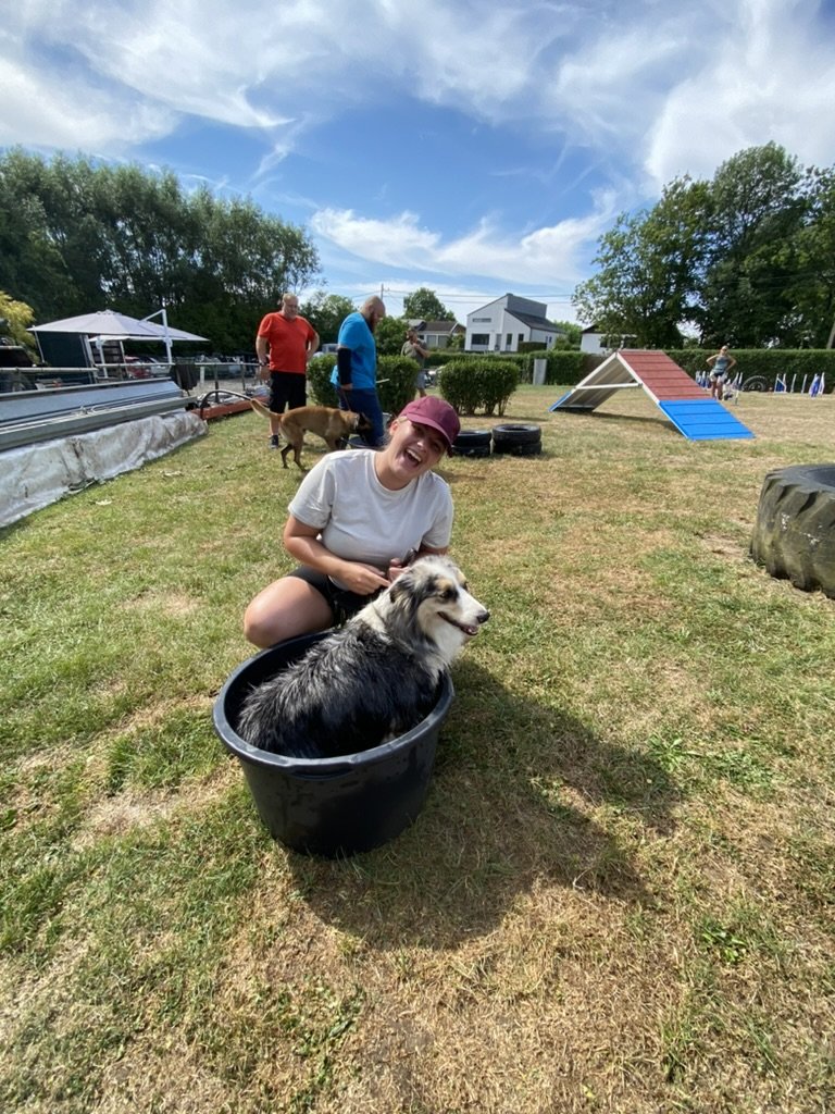 Lachende cursiste met haar hond in een badkuip op het trainingsveld